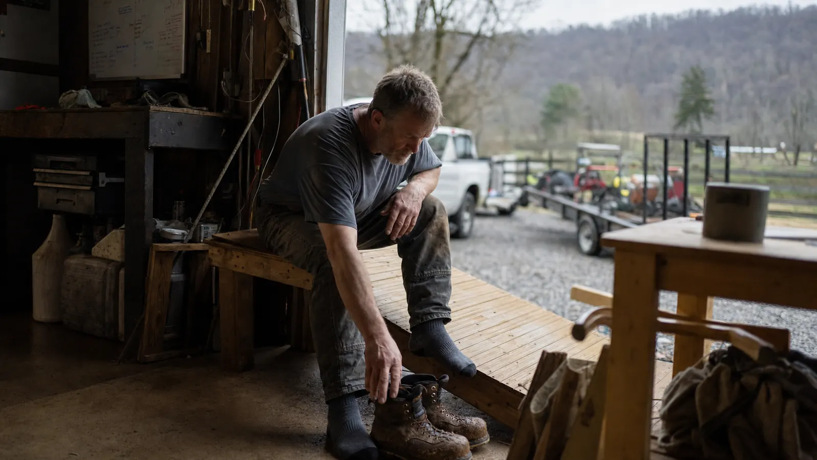 Man stepping off a slant board and pulling on work boots in a garage doorway